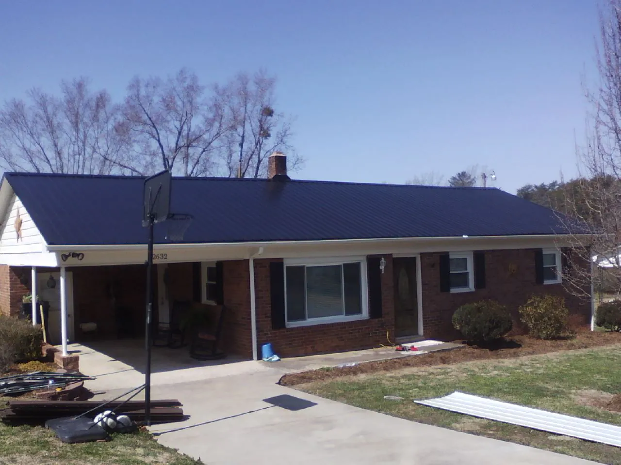 Finished dark blue metal roof on a brick ranch with a carport in Calhoun