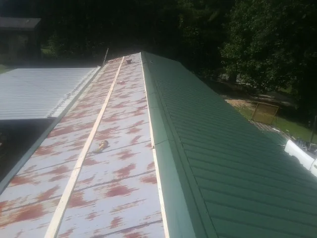 Old rusted panels beside newly installed green metal roofing — Wind Damage Roof Repair by Roofing Brothers in Calhoun