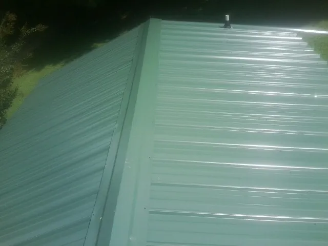 New green metal panels meeting at the ridge of a roof — Flat Roof Repair work by our crew in Calhoun