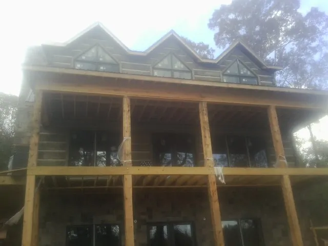 Dormers and porch framing on a large log home under construction — Roof Coating work by our crew in Calhoun